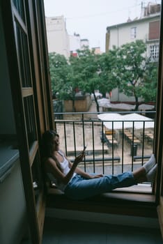 A person blissfully enjoying their leisure time in a cozy window nook with a beautiful scenic view outside