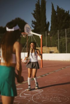 Two young girls are joyfully engaged in a lively and playful sports activity outdoors under the bright sun