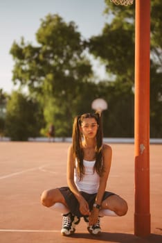 A young girl is squatting on a basketball court, having a great time enjoying a sunny day alongside her friends