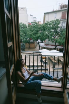 A person is happily enjoying a serene moment by the window, surrounded by lush greenery in a cozy atmosphere