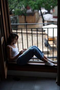 A young woman finds peace as she relaxes in a cozy window nook, deeply lost in thought and surrounded by nature