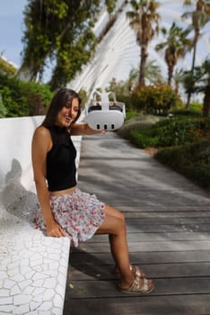 Amidst lush greenery combined with modern architecture, a stylish young woman confidently showcases her drone