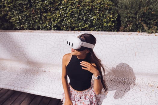 A young woman joyfully engages with a VR headset, fully embracing modern technology in a stunning outdoor setting