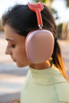 A young woman sporting trendy headphones is capturing a moment of modern lifestyle while enjoying the outdoors