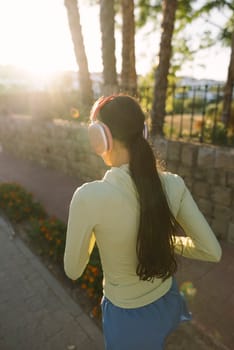 A woman is jogging outdoors, fully enjoying the warmth of the sunlight in a serene and beautiful natural setting
