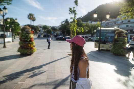 A young woman happily enjoying a sunny day in a lively and vibrant town square that is surrounded by beautiful greenery