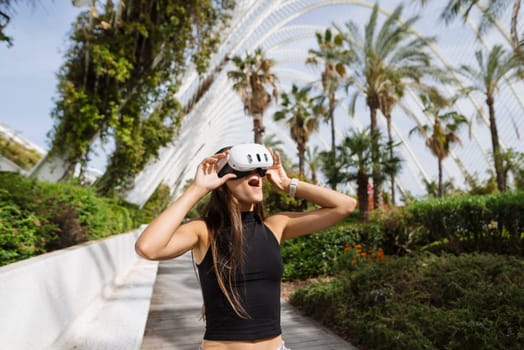 A young woman immersed in virtual reality, surrounded by vibrant greenery and sleek modern architecture