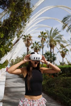 A young woman is immersed in a captivating virtual reality world with palm trees and modern architecture