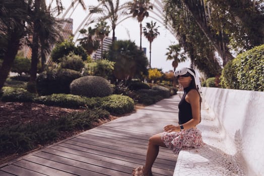 A woman is enjoying a calm and serene moment while sitting on a bench surrounded by lush tropical greenery