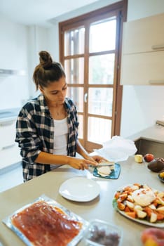 A young woman is skillfully slicing fresh ingredients in a modern kitchen, fully embracing the joy of home cooking