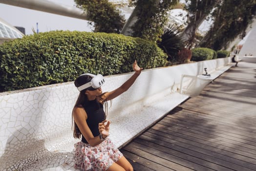 A vibrant young woman enjoys a leisurely moment outdoors, partaking in modern activities under the sunshine