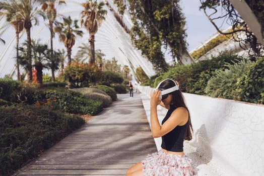 A stylish young woman is seen enjoying a moment of relaxation in a lush, vibrant, modern garden setting