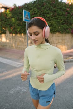 A young woman is leisurely enjoying her jog while wearing casual sportswear, listening to music through headphones