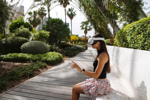 A woman experiences virtual reality while seated in a vibrant garden, blending nature and technology.