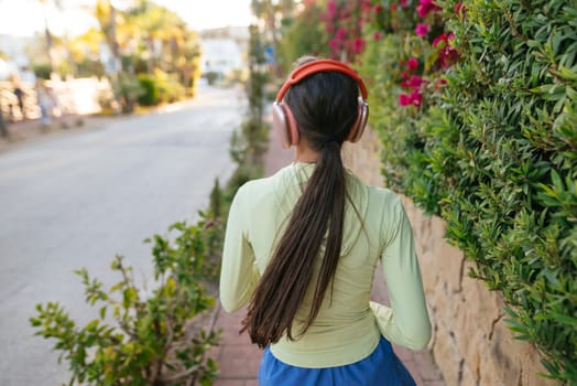 A young girl happily enjoys a delightful stroll while listening to lively music surrounded by vibrant flowers in bloom