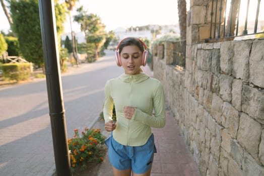 A young woman is thoroughly enjoying her morning jog with headphones on, surrounded by beautiful nature all around her