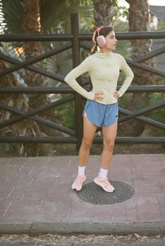 A young woman poses confidently in a fashionable athletic outfit against a beautiful outdoor backdrop