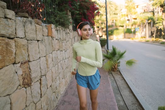A young woman finds joy and thrill while jogging along a beautiful treelined path in a vibrant outdoor setting