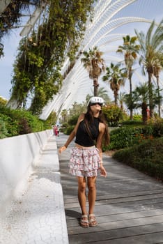 A trendy young woman poses in a skirt and helmet at a sunny park, embodying urban lifestyle and leisure.