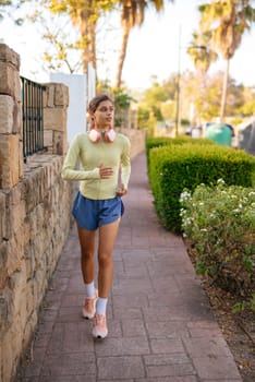 A young woman jogs energetically on a sunny path, wearing vibrant activewear and enjoying her exercise