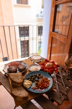An exquisite and beautiful array of gourmet snacks is elegantly displayed on a rustic table on a sunny balcony