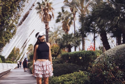 A stylish young woman stands confidently near vibrant tropical foliage, capturing a tranquil moment amid nature
