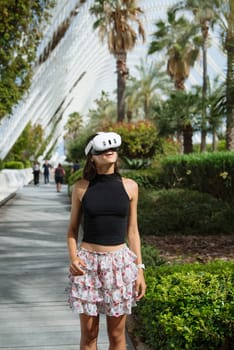 A woman wearing a VR headset thoroughly enjoys a captivating and immersive experience surrounded by lush palms
