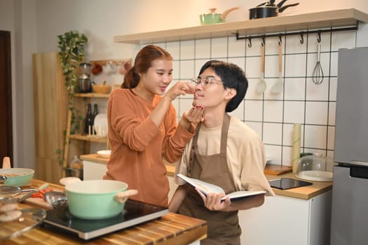 Happy young couple chatting and enjoying their lunch in domestic kitchen.