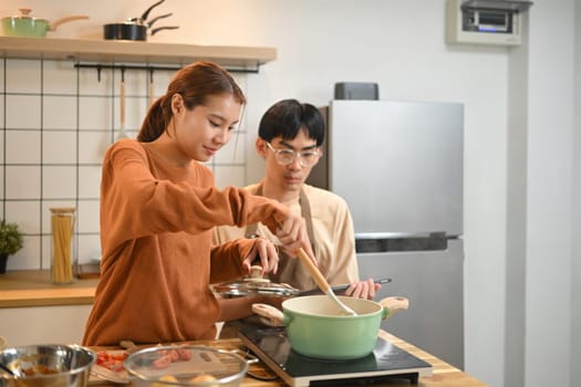 Happy young couple cooking dinner together in kitchen. Relationships and happy domestic life.