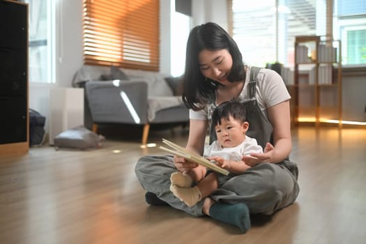 Affectionate mother reading a story to her toddler boy in living room. Childcare and family concept.