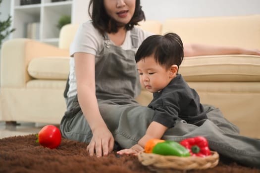 Adorable toddler boy and mother playing with colorful toys on rug. Parenting and childcare concept.