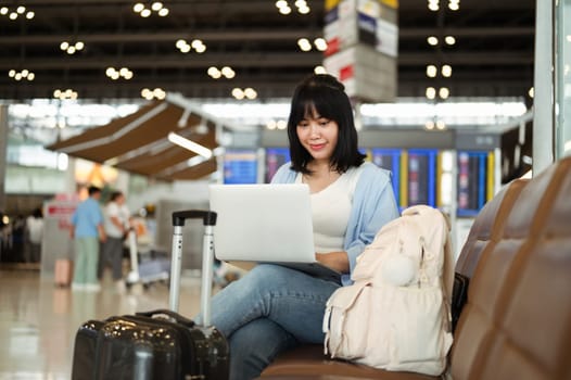 Pretty young woman using laptop in airport terminal waiting for her flight.
