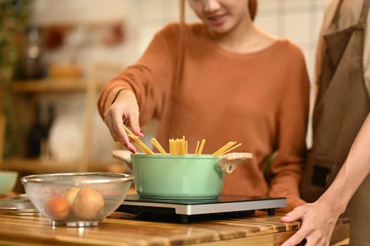 Happy young couple cooking pasta together in the kitchen. Relationships and happy domestic life.