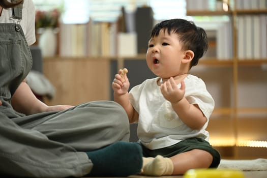 Little toddler boy playing with toys on wooden floor at home. Child development and learning concept.
