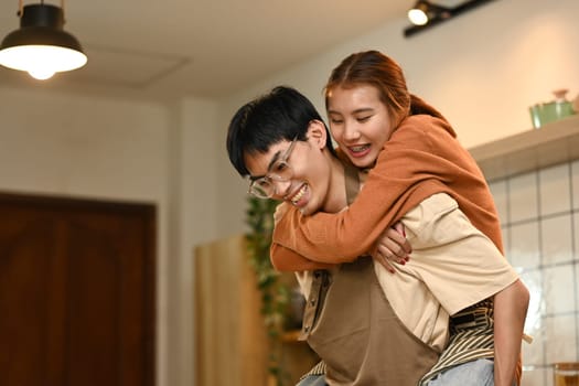 Playful young couple preparing meal and sharing a romantic moment in kitchen.