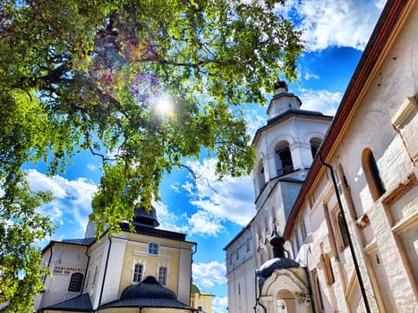 Visitors enjoy the tranquil atmosphere of Kirillo-Belozersky Monastery, set against a vibrant sky and lush greenery in Kirillov.