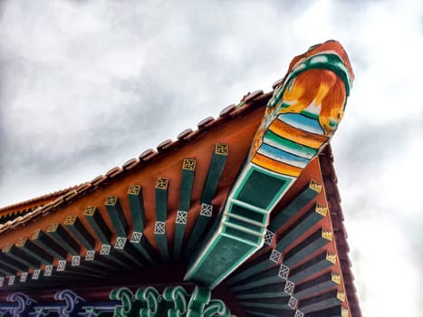 The vibrant eaves of an ornate temple roof showcase stunning craftsmanship against a moody sky.
