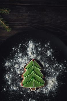 New year homemade gingerbread as firtree on the plate on dark wooden background. New Year or Christmas holiday concept