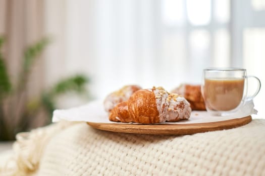 Delicious fresh french croissants and glass of coffee on wooden tray for breakfast in bed in the morning, tasty breakfast