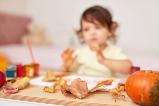 autumn background. happy little child girl painting autumn leaves. focus on leaves