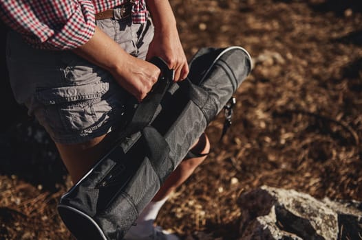 A close-up image of a person in casual outdoor attire holding a portable folding stool while outdoors, emphasizing readiness and practicality.