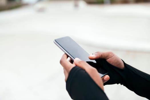 crop of the hands of an anonymous ethnic female text messaging on mobile phone with black screen in city, concept of technology of communication