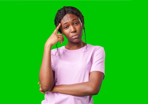 Thoughtful woman pondering in front of a bright green background during a casual moment close up