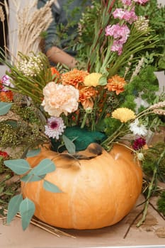 Flower arrangement in a pumpkin, autumn interior decor. Creating handmade autumn decor