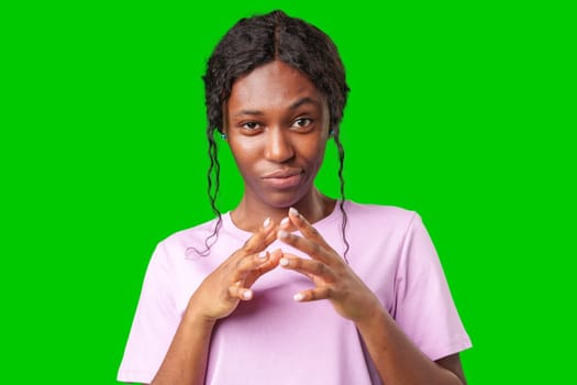 Young woman with curly hair shows a skeptical expression against a bright green background in studio
