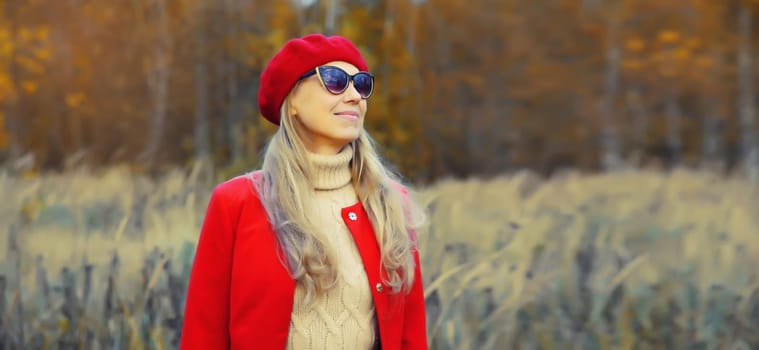 Autumn portrait of beautiful happy mature woman in red french beret hat, jacket, glasses, looking away outdoors