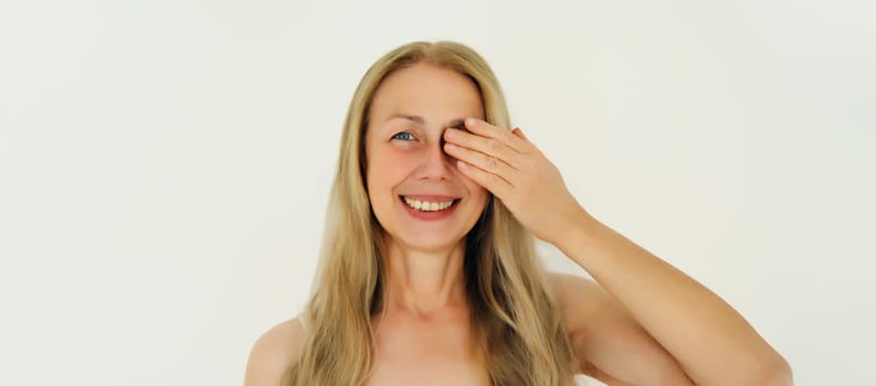 Natural beauty portrait of happy smiling mature 50s aged woman covering her eye looking at camera on white background