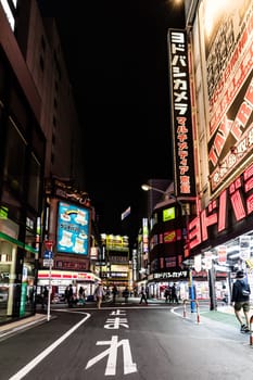 TOKYO, JAPAN - MAY 12 2019: Neon signs illuminate Tokyo’s busy Shinjuku neighborhood at night around Yodobashi camera store