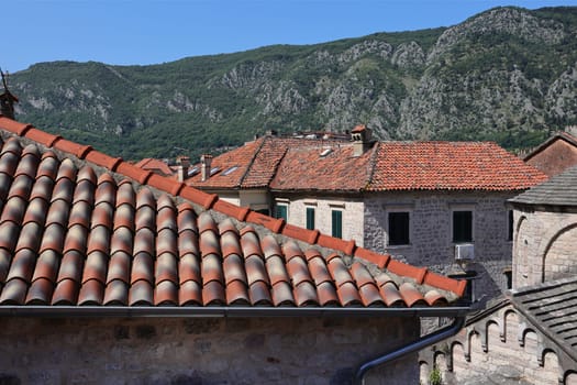 Roof texture seamless, roofs of houses covered with old natural tiles against the backdrop of the sky and mountains.