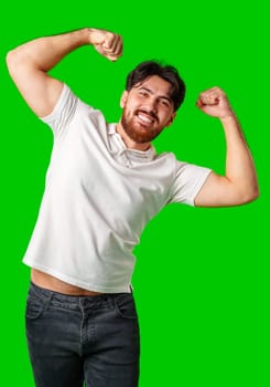 Happy man celebrating success with raised fists, wearing a white shirt against a bright green background close up